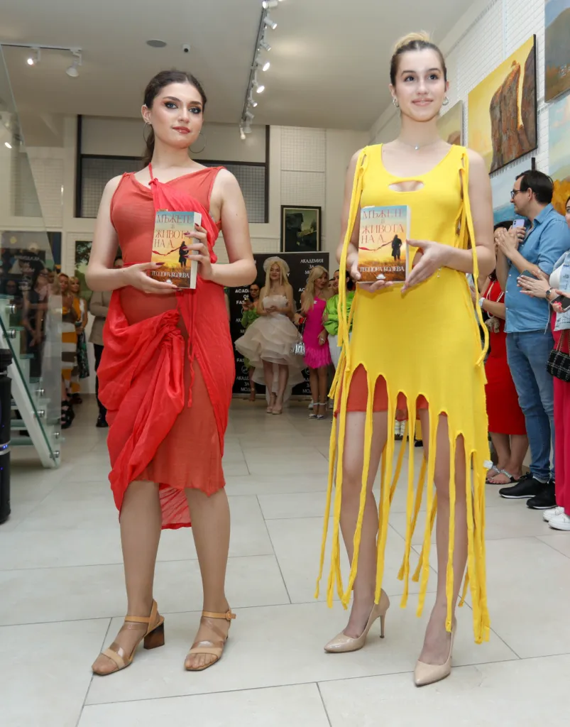 Моделите Кая Ценкова и Мина Сапаревска, облечени в тоалети на Аксел Харди и държейки книгата, вдъхновена от живота на дизайнерката.
Фото: © Академия за мода / Петър Станев